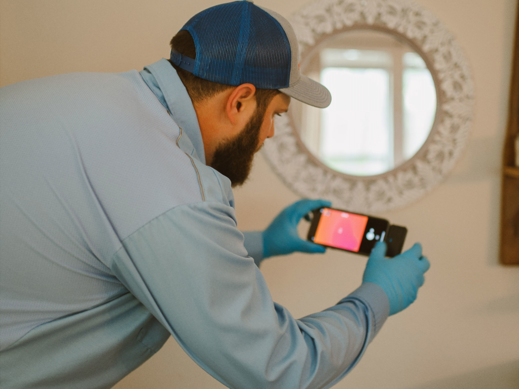 Pest control technician useing thermal imager to inspect for termites
